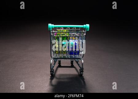 petit panier en métal plein de cadeaux colorés, isolé dans le noir, shopping en ligne, vente d'hiver, supermarché, Promotion à prix réduit et tarif « Black Friday » Banque D'Images