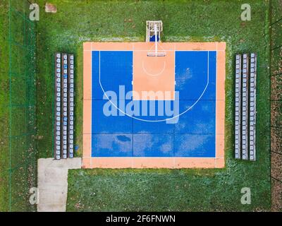 Terrain de basket-ball coloré d'en haut. Terrain de sport extérieur avec surface bleue et orange pour jouer au basket-ball, lampes et bancs pour les spectateurs Banque D'Images