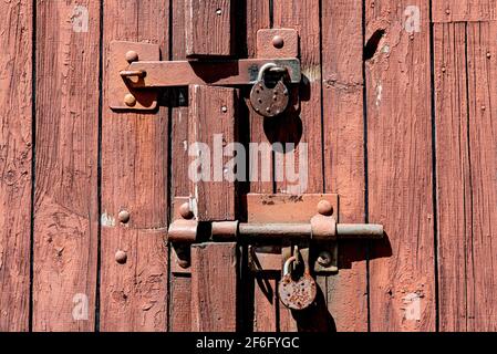 Ancienne porte de garage rouillée en bois grundy avec serrure et cadenas. Gros plan de la serrure rétro rouillée sur la porte fermée Banque D'Images