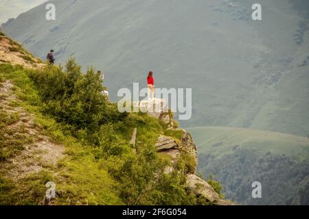 Fille debout sur l'affleurement regardant au-dessus de Devil's Valley dans le Montagnes du Caucase de la République de Géorgie avec des amis derrière prise de photos avec ph Banque D'Images