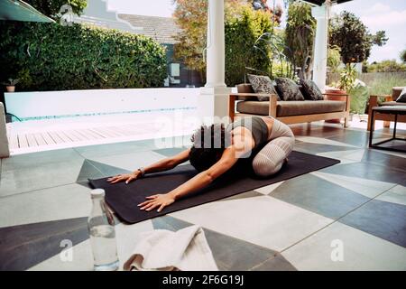 Belle femme ethnique stretching pratiquant pilates à l'extérieur de la maison Banque D'Images
