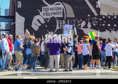 Les manifestants se promènent devant la fresque de bois Guthrie qui dit cette machine Tue les fascistes n Tulsa Oklahoma USA 3 24 2018 Banque D'Images