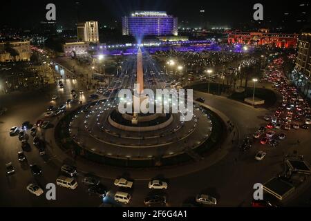 31 mars 2021, Egypte, le Caire: Une vue générale de la place El-Tahrir avec des véhicules traversant le rond-point principal orné de l'Obélisque des statues de Ramses II et Rams. Selon le ministère égyptien du Tourisme et des Antiquités, 22 momies seront transférées du Musée égyptien de Tahrir au Musée national de la civilisation égyptienne de Fustat. Les momies qui seront transférées comprennent Pharaon Ramses II; Pharaon Ramses IX; Pharaon Ramses VI; Pharaon Ramses V; Pharaon Seti I; Pharaon Seqenenre; et Pharaon Thutmose III, ainsi que la reine Hatshepsout; la reine Meritamun, la femme de Banque D'Images