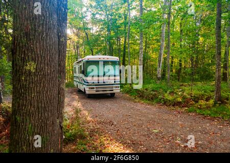 Une ancienne classe UN camping-car camping-car van maison garée dans un camping boisé, Etats-Unis. Banque D'Images