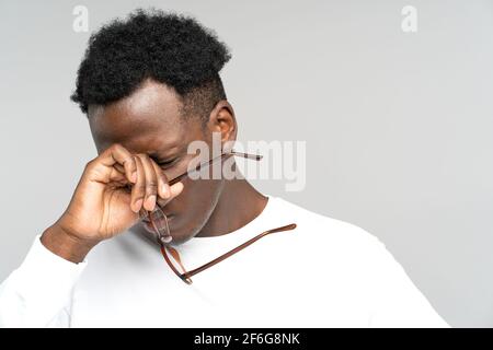 Épuisé Black man enlever des lunettes se frottant les yeux se sent fatigué après le travail sur ordinateur portable. Travail excessif. Banque D'Images