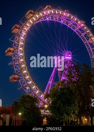 La roue du Prater Ferris : Riesenrad Wurstelprater après la tombée de la nuit : le célèbre parc de loisirs de Vienne, l'attraction la plus célèbre d'une immense roue antique de ferris juste après le coucher du soleil, éclairée par ses nombreuses lumières contre un ciel sombre. Banque D'Images