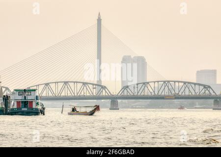 Un bateau à longue queue avec le pont bouddhiste traversant la rivière Chao phraya. Banque D'Images