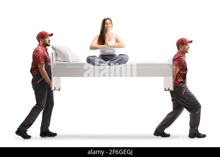 Jeune femme en pyjama assise sur un lit faisant du yoga et des déménageurs transportant le lit isolés sur fond blanc Banque D'Images