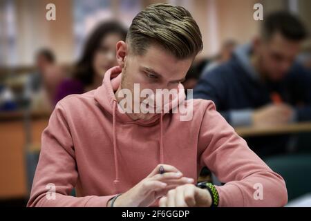 un jeune étudiant utilise une montre intelligente de tricherie dans un cours de mathématiques à l'université Banque D'Images