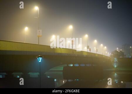 Brouillard nocturne sur la Vistule, Cracovie, Pologne, avec la perspective de feux de rue éclairés sur le pont vide de Debnicki Banque D'Images