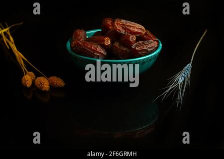 Dattes séchées sur une table en bois, plats argentés en gros plan. Composition de dattes séchées dans un plat de ramadan sur une table en bois. Banque D'Images