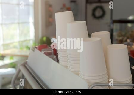 Beaucoup de tasses en papier blanc jetables sur machine à café avec fond de cofe shop. La pile de gobelet en papier dans le café. Gros plan recyclez le gobelet en papier blanc Banque D'Images
