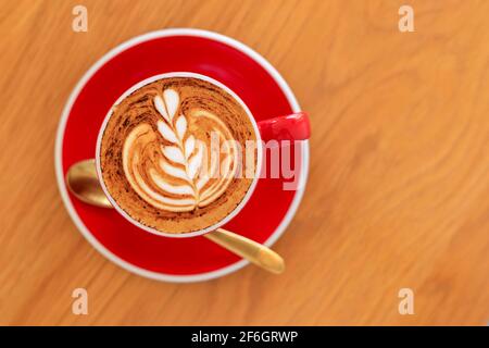 Mise au point douce vue du dessus gros plan d'un espresso chaud, café latte dans une tasse en céramique rouge sur fond de table en bois flou. Banque D'Images