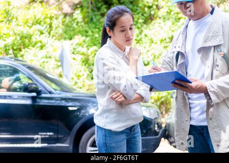 Accident de voiture accident de voiture la femme parle de l'accident à l'agent d'assurance. L'agent d'assurance écrit le document dans le presse-papiers de l'incident pour cla Banque D'Images