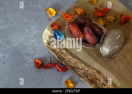 Dattes séchées sur une table en bois, plats argentés en gros plan. Composition de dattes séchées dans un plat de ramadan sur une table en bois. Banque D'Images