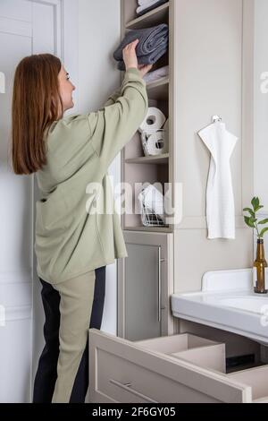 Les mains de la femme mettent ou présentent une serviette blanche enroulée propre en coton biologique. Banque D'Images