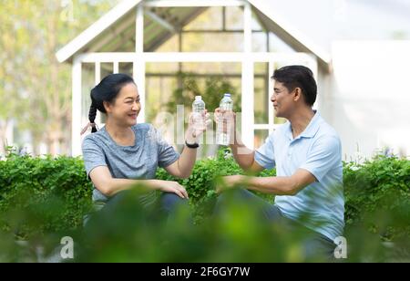 Les personnes en retraite se réjoument de boire de l'eau après l'exercice, le couple asiatique d'âge moyen boit de l'eau Banque D'Images