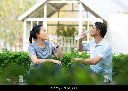 Les personnes en retraite se réjoument de boire de l'eau après l'exercice, le couple asiatique d'âge moyen boit de l'eau Banque D'Images