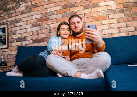 Vue de face d'un jeune couple heureux et joyeux ayant en ligne webcam chat avec via appel vidéo sur téléphone mobile. Banque D'Images