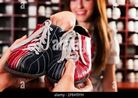 Une femme emprunte des chaussures pour jouer au bowling dans un