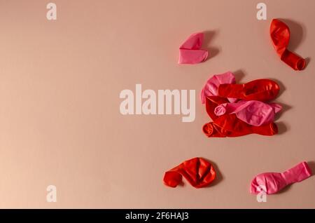 Composition minimaliste avec ballons dégonflés sur fond rose. Plusieurs nouveaux ballons rouges et roses. Vue de dessus, plan d'appartement. Banque D'Images