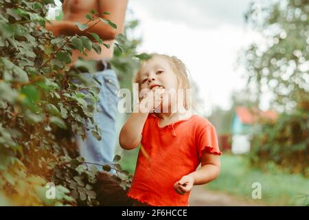 Little girl eating groseilles dans le jardin d'été Banque D'Images