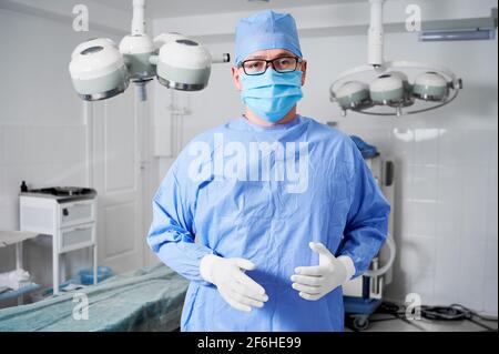 Chirurgien masculin dans un masque médical debout dans la salle d'opération. Banque D'Images