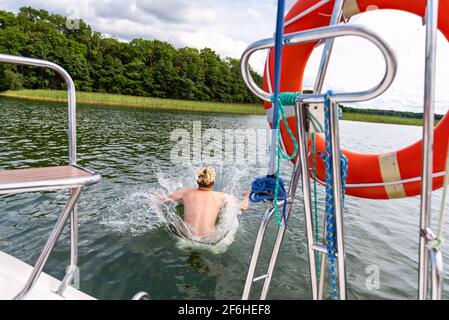 Heureux fou adulte homme ayant le plaisir de sauter dans l'eau du lac. Vacances d'été, concept de vacances pour les jeunes. Banque D'Images