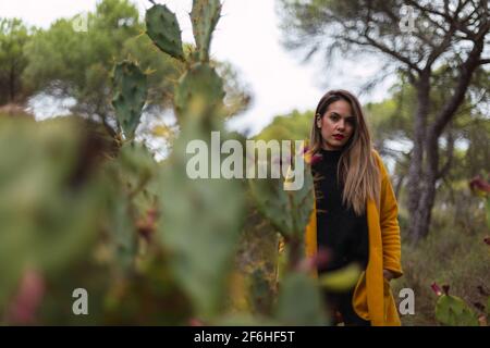 Fille dans un manteau jaune dans la forêt ou le parc au printemps. Fille appréciant son temps dehors dans le parc. Banque D'Images