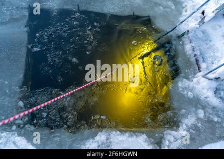Un plongeur sous l'eau brille avec une lampe de poche torche une entrée de trou de glace avec un pour la plongée sous-marine sur glace plongée Banque D'Images