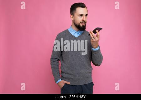 Photo prise de beau positif belle apparence jeune homme portant décontracté ensemble élégant poising isolé sur fond avec espace vide main dans la main Banque D'Images