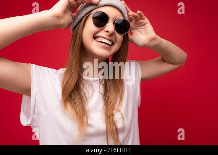 photo en gros plan d'un beau sourire positif jeune blond foncé femme portant des vêtements décontractés et des lunettes de soleil stylées isolées sur coloré Banque D'Images