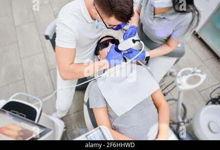 Médecin et assistant examinant les dents du patient à l'aide d'un scanner intrabuccal. Banque D'Images