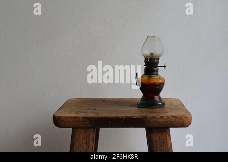 Gros plan lampe à kérosène vintage sur chaise en bois vintage contre mur de ciment blanc Banque D'Images