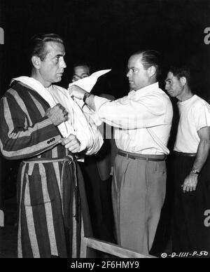 HUMPHREY BOGART sur le set Candide avoir son bras habillé par Un homme de premier secours en studio pour une scène morte RECKONING 1947 réalisateur JOHN CROMWELL Columbia Pictures Banque D'Images