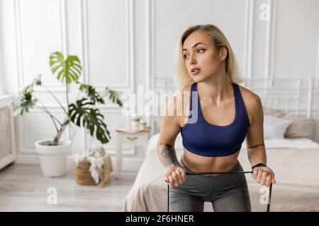 Athlétique attrayante jeune femme faisant des exercices pour les bras, en utilisant un groupe de sport. Concentrée belle fille est de l'activité dans l'élégant sportswear à Banque D'Images