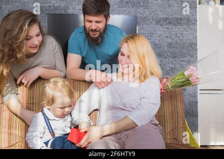 Papa avec des enfants félicitent maman pour les vacances, la fête des mères. Amusez-vous, riez et donnez des fleurs Banque D'Images