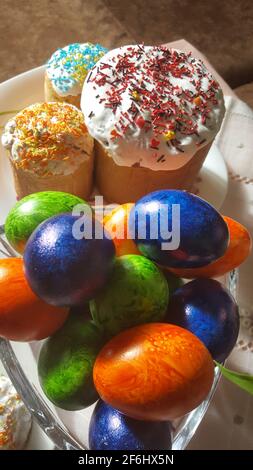 Pain ou gâteau traditionnel de Pâques avec glaçure blanche et saupoudrer d'arc-en-ciel multicolore. Gâteau de Pâques et œufs Pysanka. Vue rapprochée. Banque D'Images