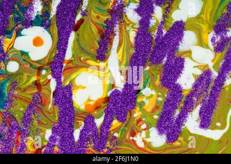 Un arrière-plan composé de nombreuses textures, formes et matériaux. Les sparkles violets sont dispersés sur un fond acrylique multicolore. Banque D'Images