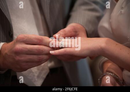 Gros plan de la mariée mettant un anneau de mariage sur le doigt du marié. Couple échanger des anneaux de mariage. Photo de haute qualité Banque D'Images