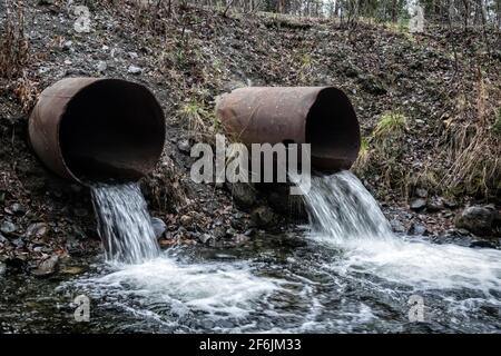Gouttière. Ruissellement d'eau provenant d'un déversoir routier (évacuation de l'eau, évacuation des eaux pluviales), de deux tuyaux et d'eau à écoulement lent (ruissellement direct) Banque D'Images