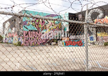 Vue à travers une clôture recouverte de barbelés à Street art couvrant chaque mur en vue dans le quartier artistique de Wynwood, Miami, Floride, États-Unis Banque D'Images