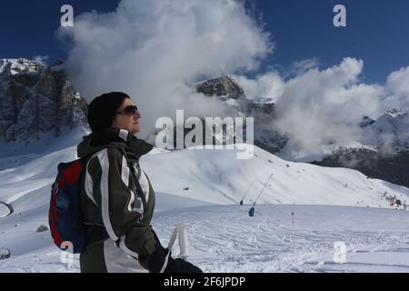 schöne Frau beobachtet vom Langkofel die schneebemattten Berge und Felsen am winterlichen Sella Joch in Südtirol in den Dolomiten Banque D'Images