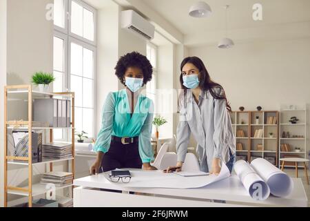 Portrait des designers et des femmes d'affaires dans les masques de visage debout en studio de bureau Banque D'Images