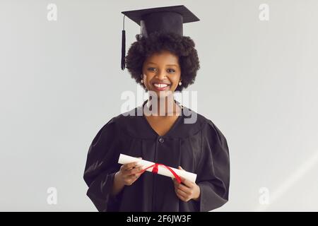 Femme afro-américaine en casquette universitaire et robe avec diplôme photo de studio Banque D'Images
