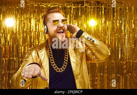 Joyeux DJ dans une veste brillante, des écouteurs et des lunettes de soleil cool jouant de la musique à la fête disco Banque D'Images