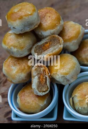 Une pâtisserie asiatique traditionnelle ou Tao SOR sur une table rustique en bois. Pâtisserie sucrée chinoise fourrée de pâte de haricots mung, de taro et d'œuf salé, l'un des populaires s. Banque D'Images