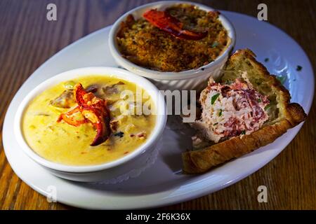 Une assiette de plats à base de homard servis en Nouvelle-Écosse, au Canada. La chaudrée de homard, le homard au mac et au fromage et la viande de homard sur croissant Banque D'Images