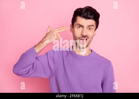 Photo de fatigué bouleversé jeune gars porter un chandail violet montrant pistolet à main me demandant tuer isolé pastel couleur rose fond Banque D'Images