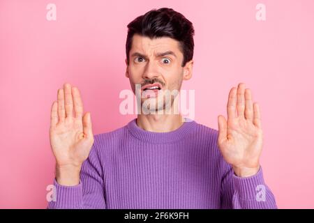 Portrait d'un sympathique type perplexe montrant des palmiers stop signe éviter isolé sur fond rose pastel Banque D'Images